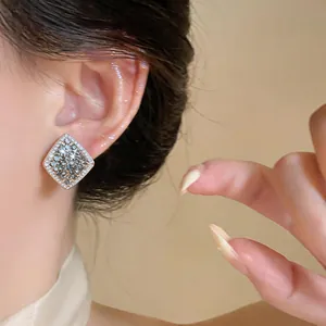 Close-up of a French retro style rhombus stud earring with sparkling diamond pavé.
