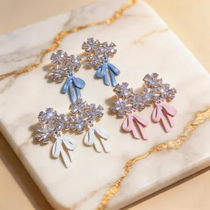 Detalle de pendientes de flores con cristales brillantes y lazos de esmalte de colores