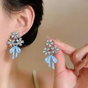 Primer plano de pendientes de plata con flores de diamante y elegantes lazos azules