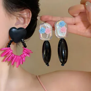 Close-up of elegant acrylic flower and heart-shaped earrings with pink fringe detail