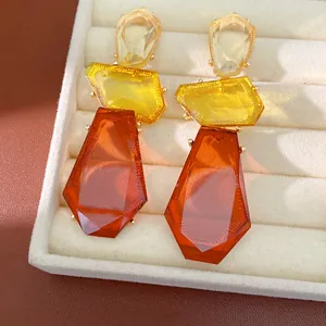Detailed macro shot of irregular amber and yellow resin geometric drop earrings in box