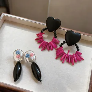 Detailed view of chic black heart earrings with pink fringe and silver rose pendant studs