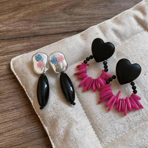 Detail of acrylic flower stud earrings and black heart earrings on a display pad