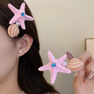 Detail of pink starfish and shell hair clip with faux pearl and blue star accent