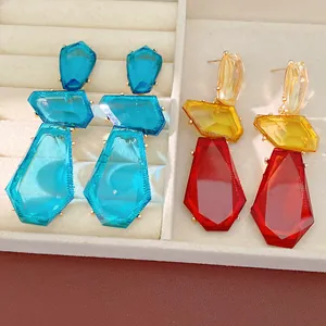 Close-up detail of geometric resin drop earrings in blue, yellow, and red colors.