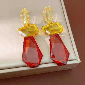 Detail of oversized irregular resin earrings in amber and yellow with silver needles