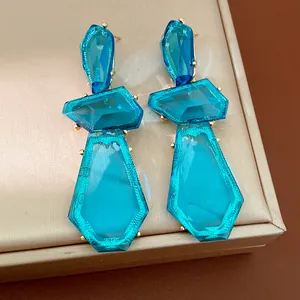 Detailed view of oversized irregular blue resin earrings with golden metal accents