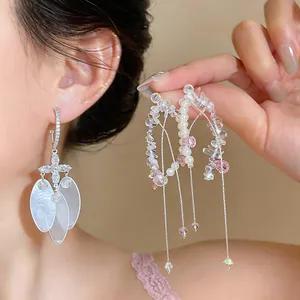 Close-up detail of elegant shell and zircon drop earrings with pearl tassels
