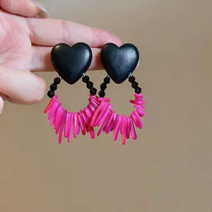 Close-up of stylish heart-shaped earrings featuring vibrant pink acrylic fringe details