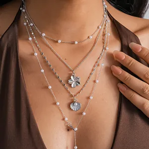 Close-up of layered silver necklace with pearl shell and flower pendants for beach style