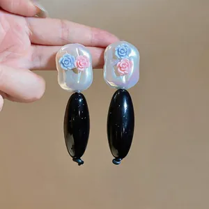 Close-up of elegant acrylic drop earrings with pink and blue resin flowers