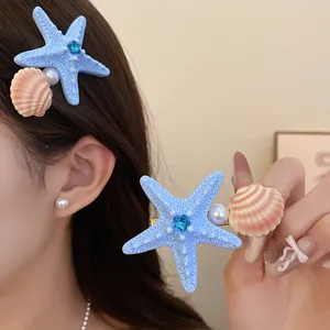 Close-up detail of starfish and seashell hair clips with pearls on side hair and hand