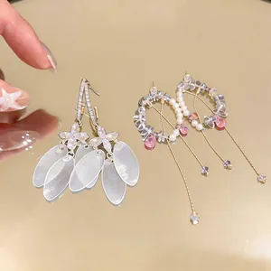 Detailed shot of silver needle fringe earrings with shell petals and pearl accents