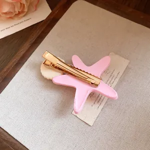 Detailed view of pink starfish and shell hair clip with secure gold metal alligator clip
