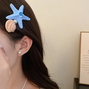 Detailed view of the blue starfish and seashell hair clip worn on the model's dark hair