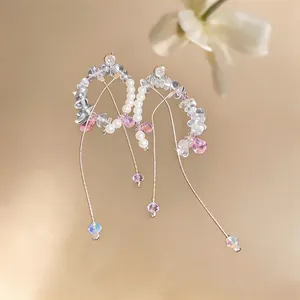 Macro detail of C-shape earrings with pearls, pink crystals, and long tassels