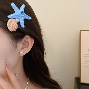 Close-up detail of a blue starfish and seashell hair clip worn on side swept hair.