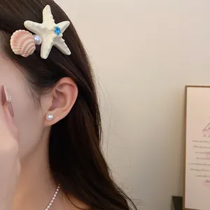 Side-view detail of a starfish and shell hair clip with pearl accents on a model