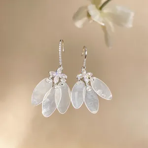 Close-up of elegant silver earrings with zircon flowers and shell leaf tassels
