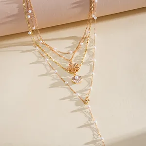 Detailed view of gold multi-layer necklace with pearl beads, shell and flower charms.