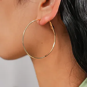 Detailed view of a large polished gold minimalist hoop earring worn elegantly on a model's ear