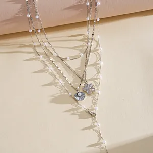 Detailed shot of multilayer silver necklace with pearls, shell and flower charms.