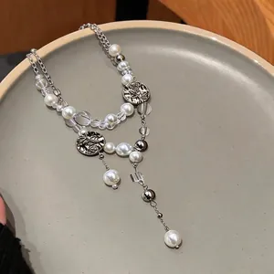 Elegant double-layer pearl necklace with vintage rose pendants on a ceramic plate