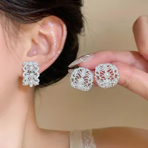 Macro view showing the intricate hollow oval design of pearl and zircon earrings