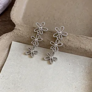 Close-up detail of elegant silver-toned hollow flower tiered clip-on earrings for women