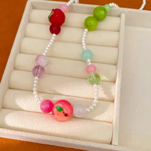 Close-up of a colorful resin apple beaded necklace displayed on a beige velvet jewelry tray