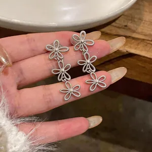 Detailed macro shot of silver hollow-out flower drop earrings for non-pierced ears