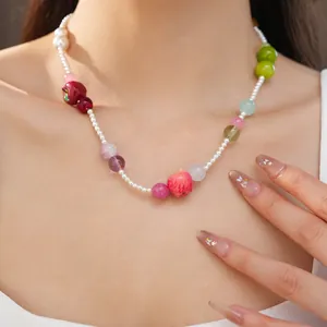 Detail shot of colorful resin apple and pearl beaded necklace on model neck