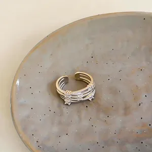Close-up of a multi-layered silver open ring with zircon stones on a ceramic plate.
