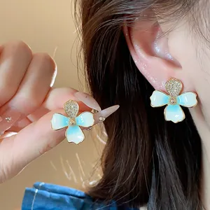 Detailed close-up of elegant light blue enamel flower earrings with sparkling zircon