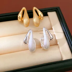 Detailed view of 18k gold plated brushed teardrop earrings in gold and silver tones