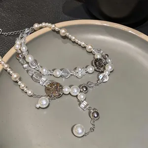 Detail shot of multi-layered pearl necklace with vintage floral engraved metal charms