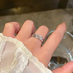 Close-up of elegant silver multi-layer zircon ring worn on finger with lace sleeve