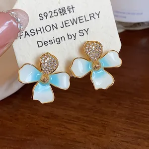 Close-up detail of 18k gold plated flower stud earrings with shimmering zircon stones