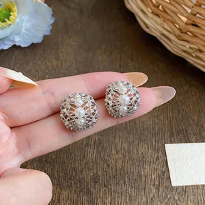 Close-up of silver-tone hollow earrings with zircon and pearl embellishments