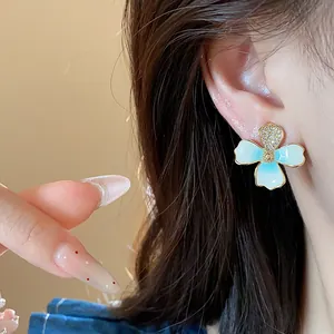 Close-up detail of a light blue enamel flower stud earring with zircon accents