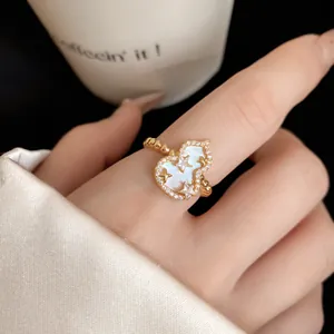 Primo piano di un anello a forma di zucca in zircone con intarsio in madreperla al dito.
