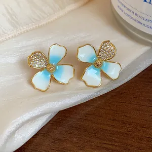 Detail shot of 18k gold plated flower earrings with blue enamel and sparkling zircons
