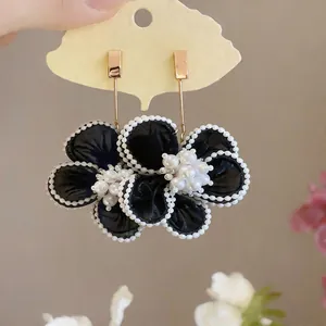 Dettaglio di eleganti orecchini a fiore in chiffon nero con accenti di perle bianche