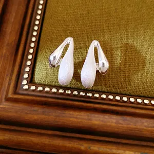 Macro view of teardrop earrings featuring a unique brushed and polished silver finish
