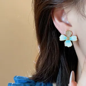 Close-up of elegant flower stud earring with light blue enamel and zircon detail