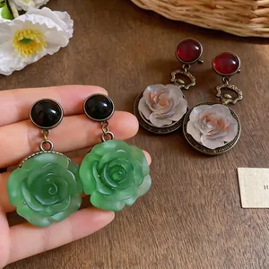 Vintage style resin rose flower pendant earrings with round stud design on wood background