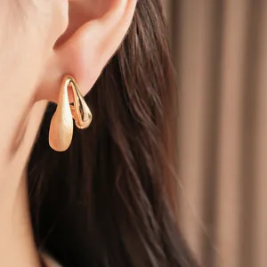 Macro view showing the detailed brushed and polished texture of these gold waterdrop earrings.