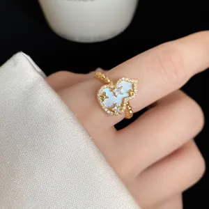 Primo piano di un anello dorato a forma di zucca con zirconi e stelle sul dito.