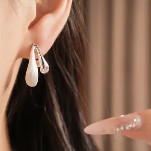 Close-up detail of minimalist brushed waterdrop silver stud earrings worn on female ear