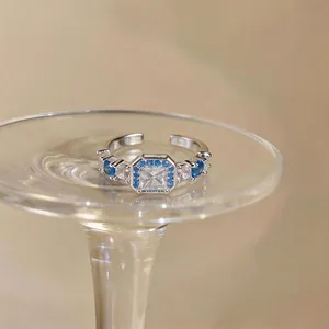 Elegante anello aperto in argento con zirconi blu e chiari su base di cristallo.